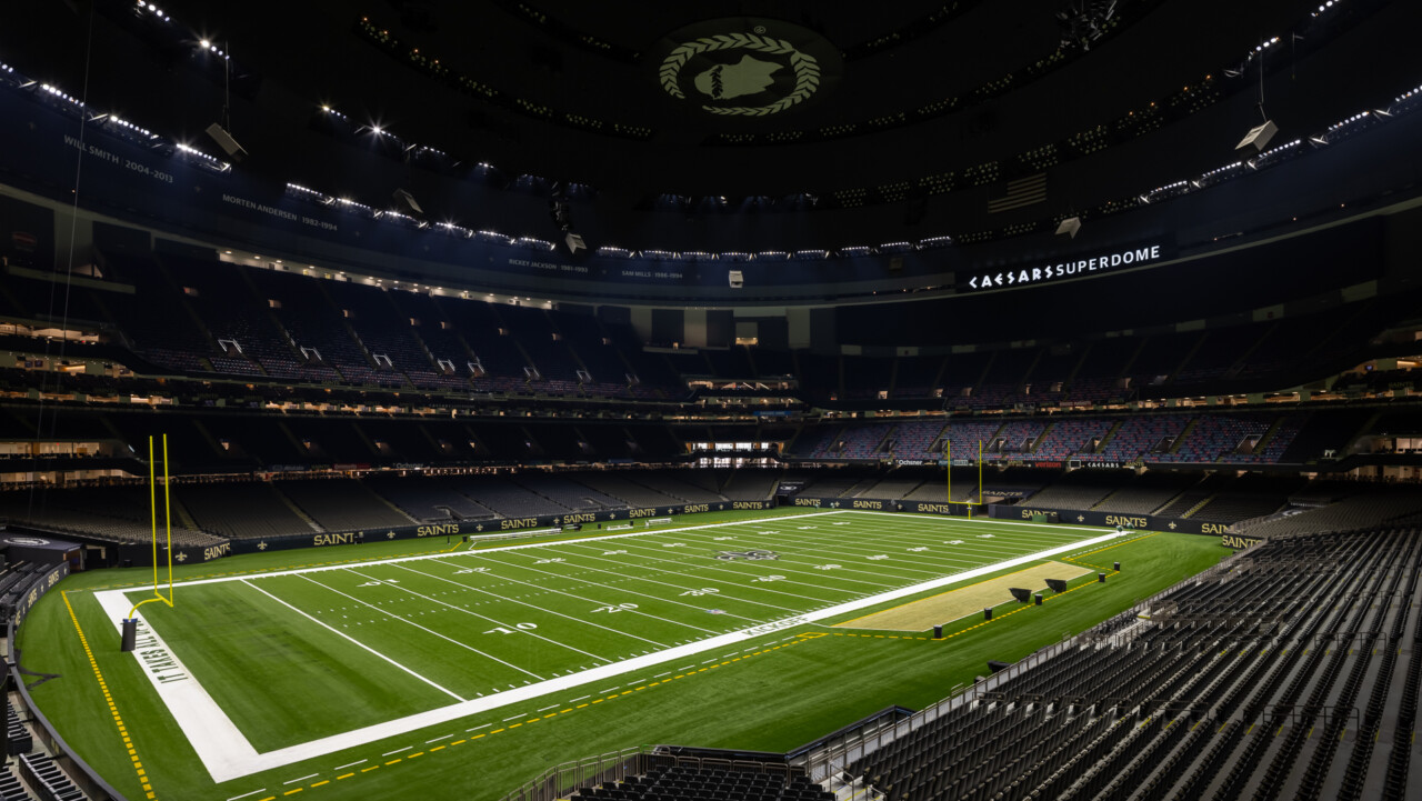New Orleans Superdome - Empty football stadium interior with bright field lighting, tiered seating, and dome ceiling with central logo