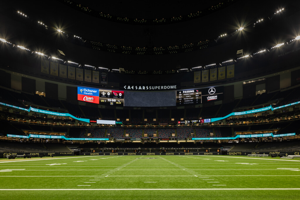 New Orleans Superdome - Interior view of a large domed stadium with field lighting, scoreboard, and seating under a dark dome ceiling