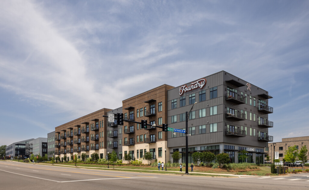 The Foundry Huntsville - Contemporary mixed-use building with brick and metal facade, ground-floor retail, residential units above, and street-level landscaping