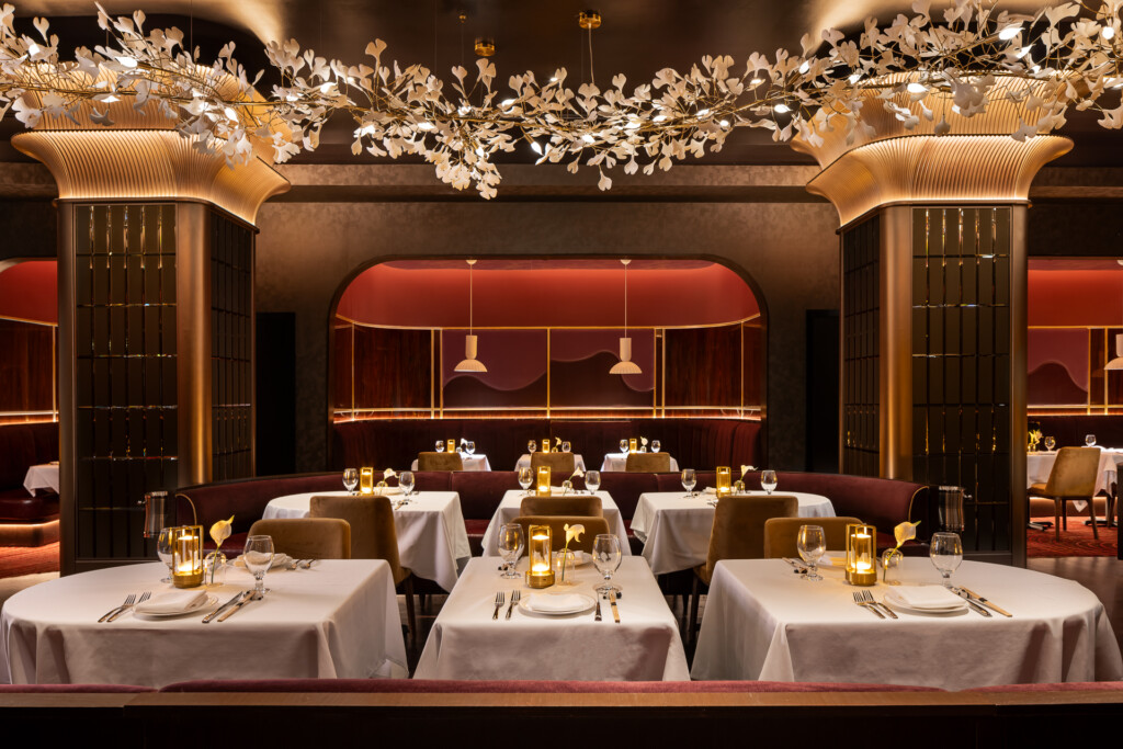 Philippe Chow - Nashville - Fine dining restaurant interior with white tablecloths, brass pendant lights, burgundy banquettes, and ornate gold leaf botanical installations overhead.