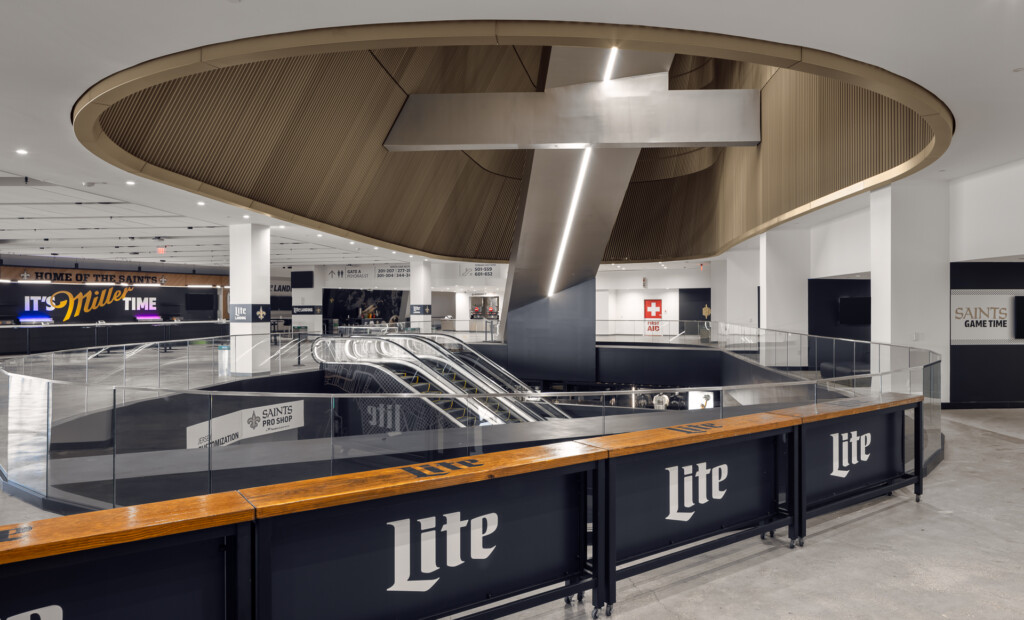 New Orleans Superdome - Spacious arena concourse featuring a dramatic curved wooden and metal ceiling element, escalators, branded concession counters, and contemporary commercial architecture