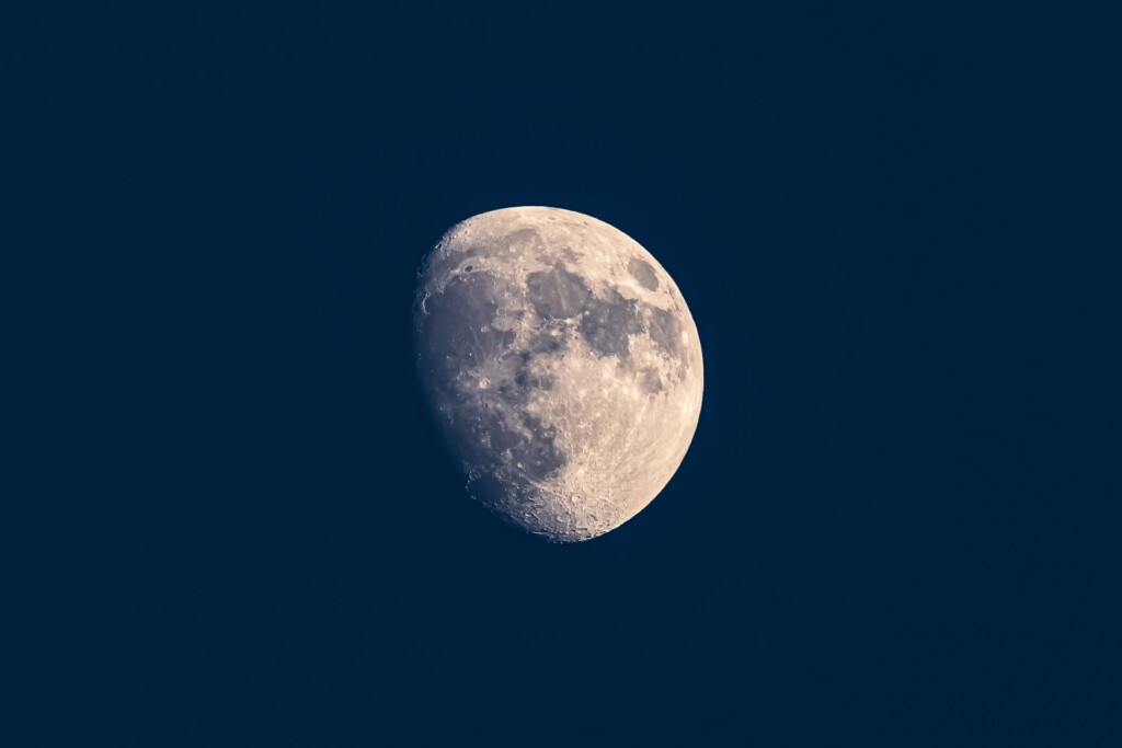 Waxing gibbous moon with visible craters and surface detail against a dark blue sky