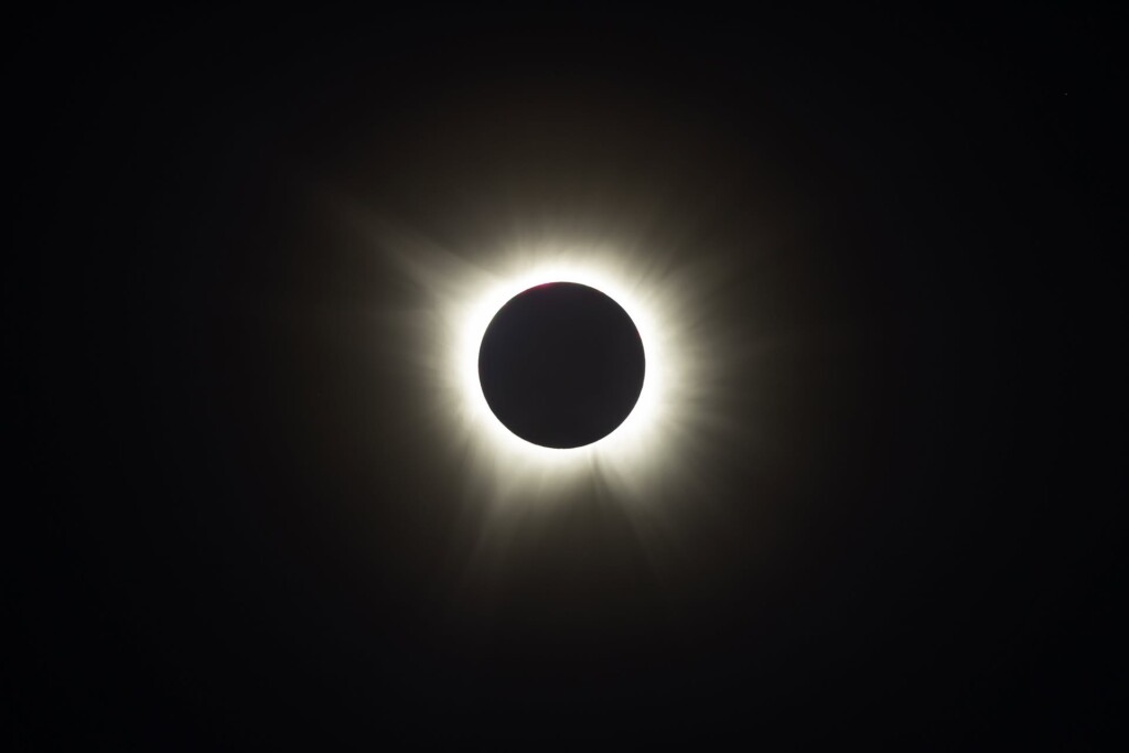 The Moon passes in front of the Sun, blocking its disk while the bright white corona radiates outward against a dark sky.